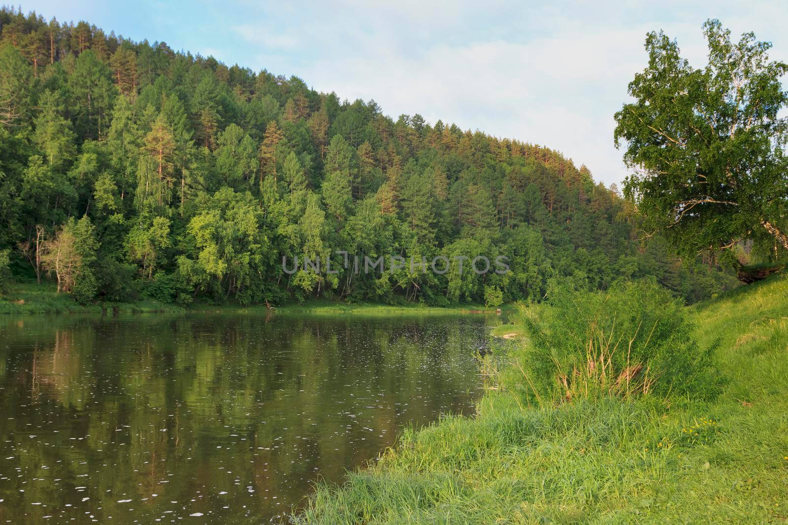 Colorful landscape with mountains and a beautiful calm river in Russia. River Ay. Summer, river rafting