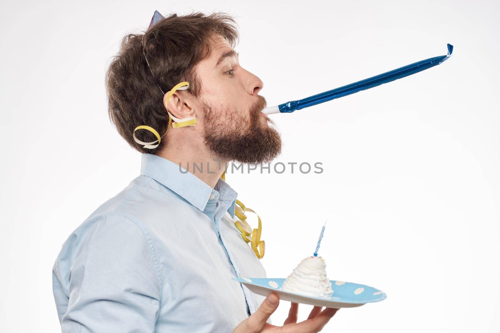 A man celebrate a birthday on a light background with a cake in a plate flute fun