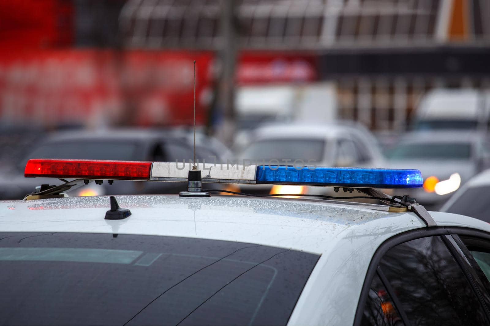 police car lights in city street at winter day with cars traffic in blurry background.