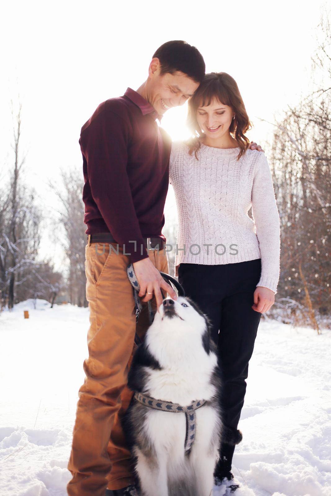Young couple with siberian husky dog in winter in the park by selinsmo