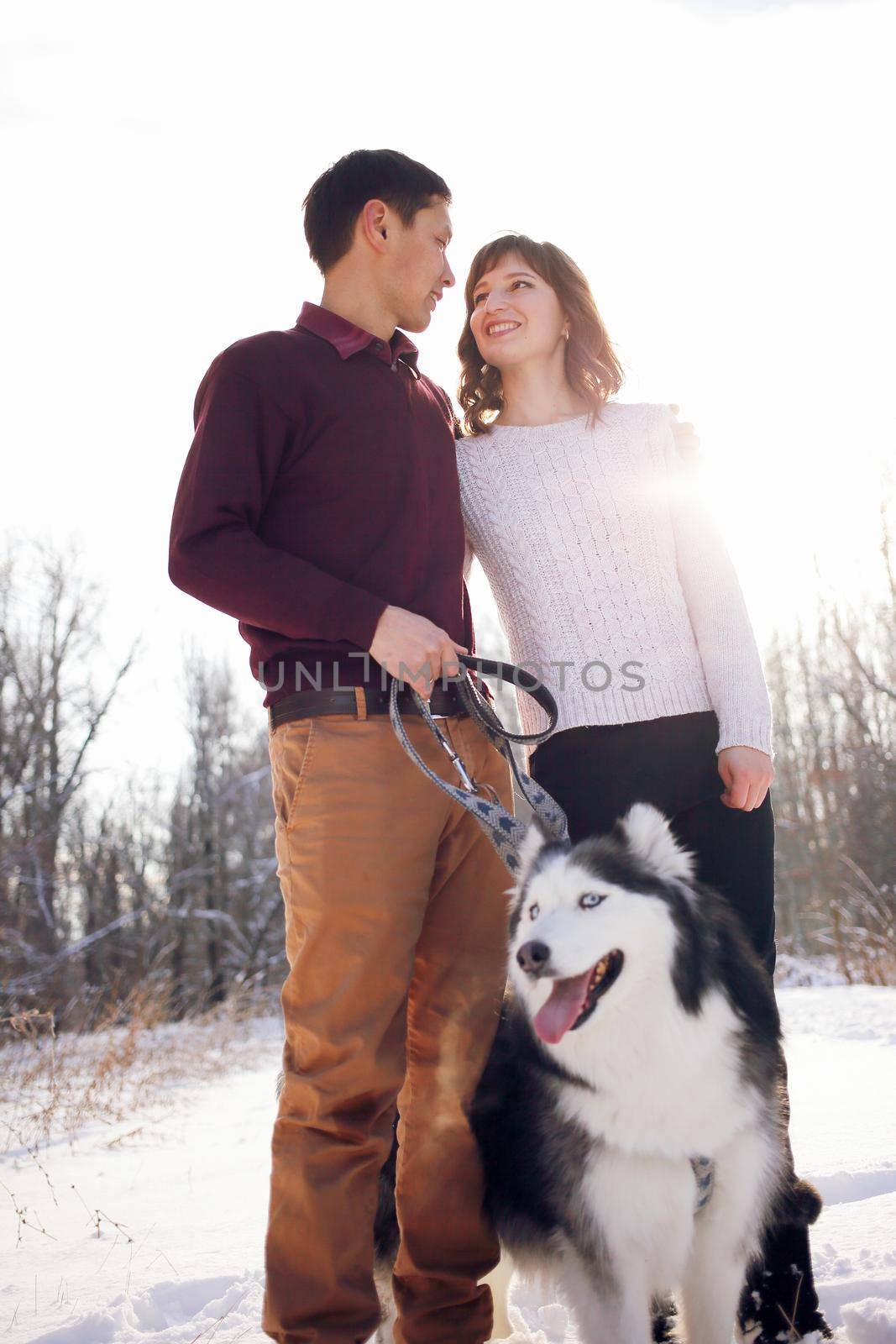Young couple with siberian husky dog in winter in the park.