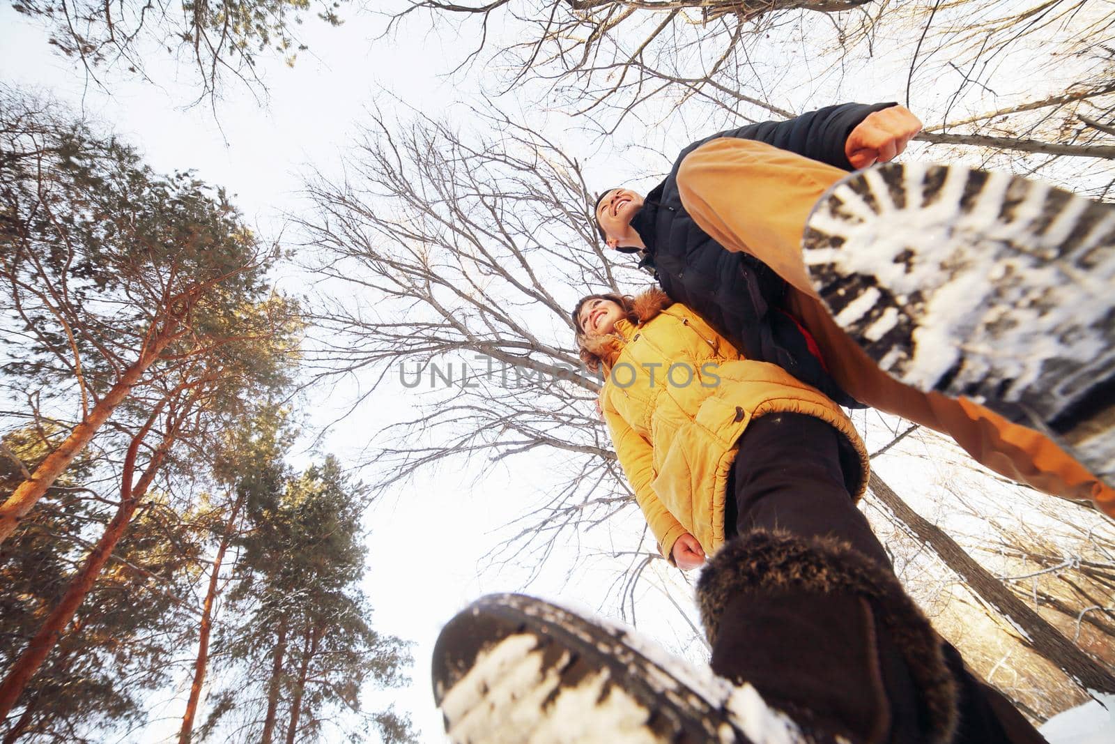 Cheerful young couple walking in the winter forest, low angle.
