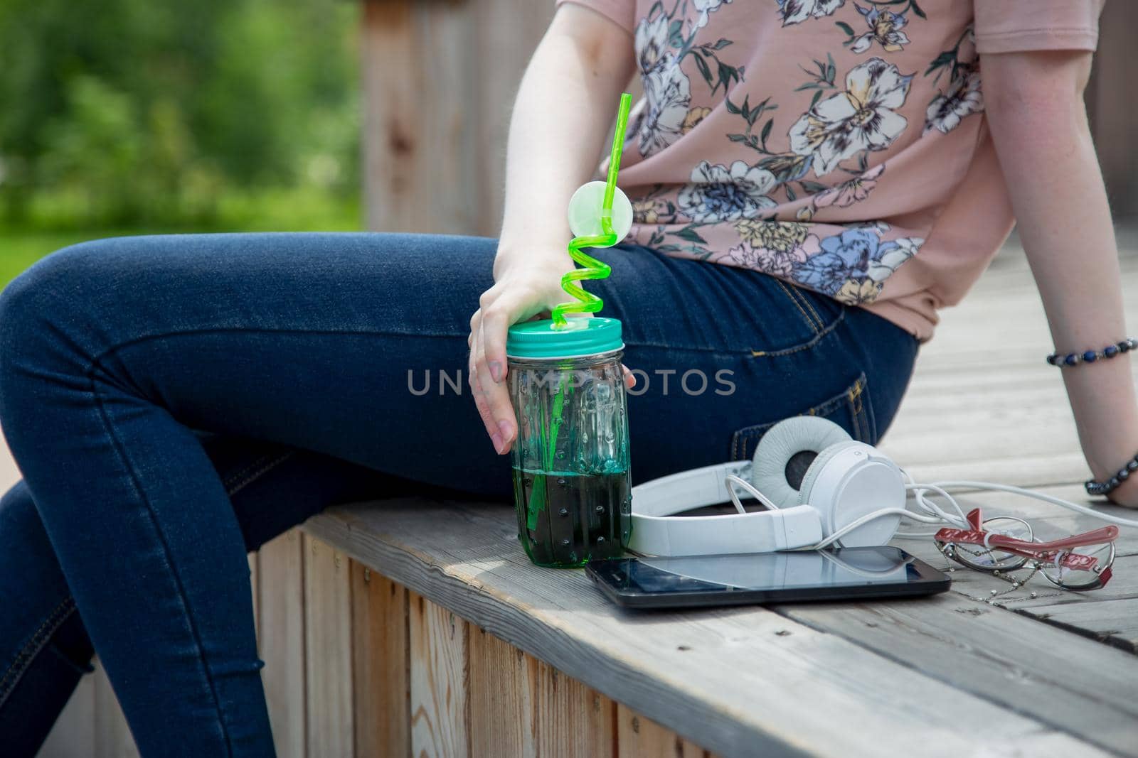 Cropped view of young girl sitting on a wooden podium in the park on a summer by galinasharapova