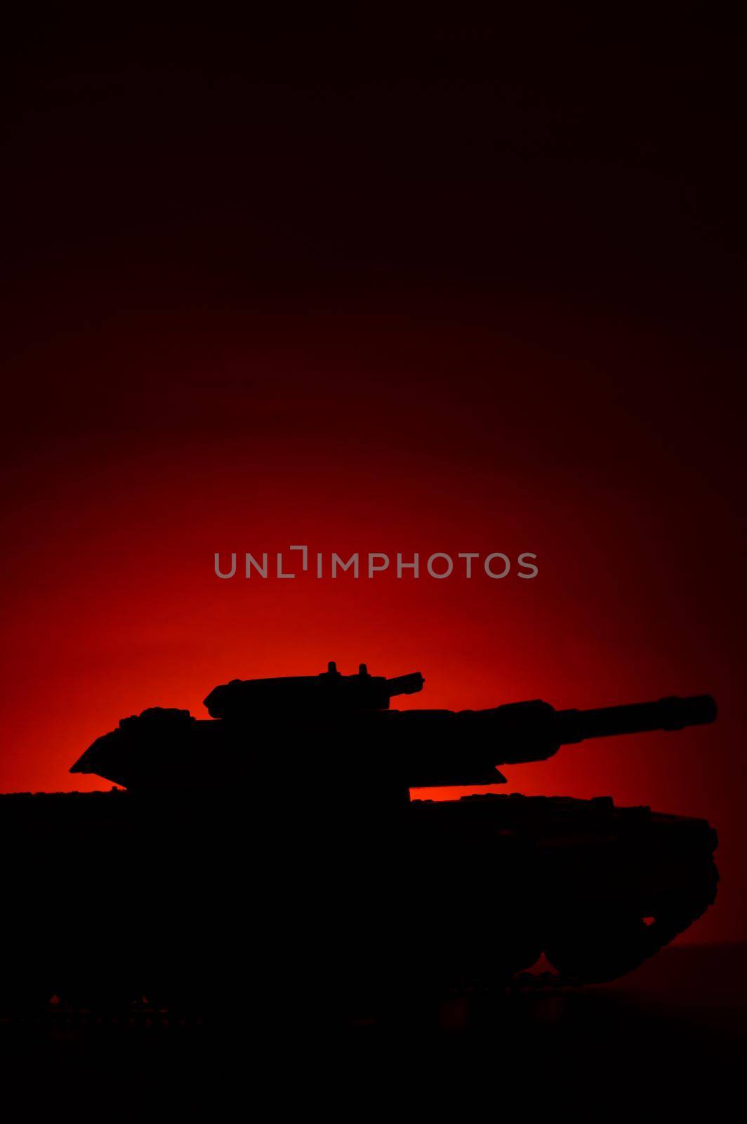 A military tank silhouette over a sunset background with deep red and orange hues which add atmospheric mood.