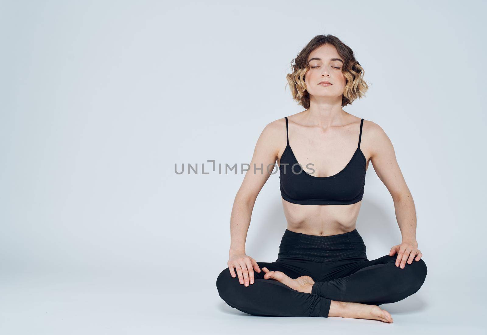 Woman with crossed legs meditate while sitting on the floor of yoga asana by SHOTPRIME