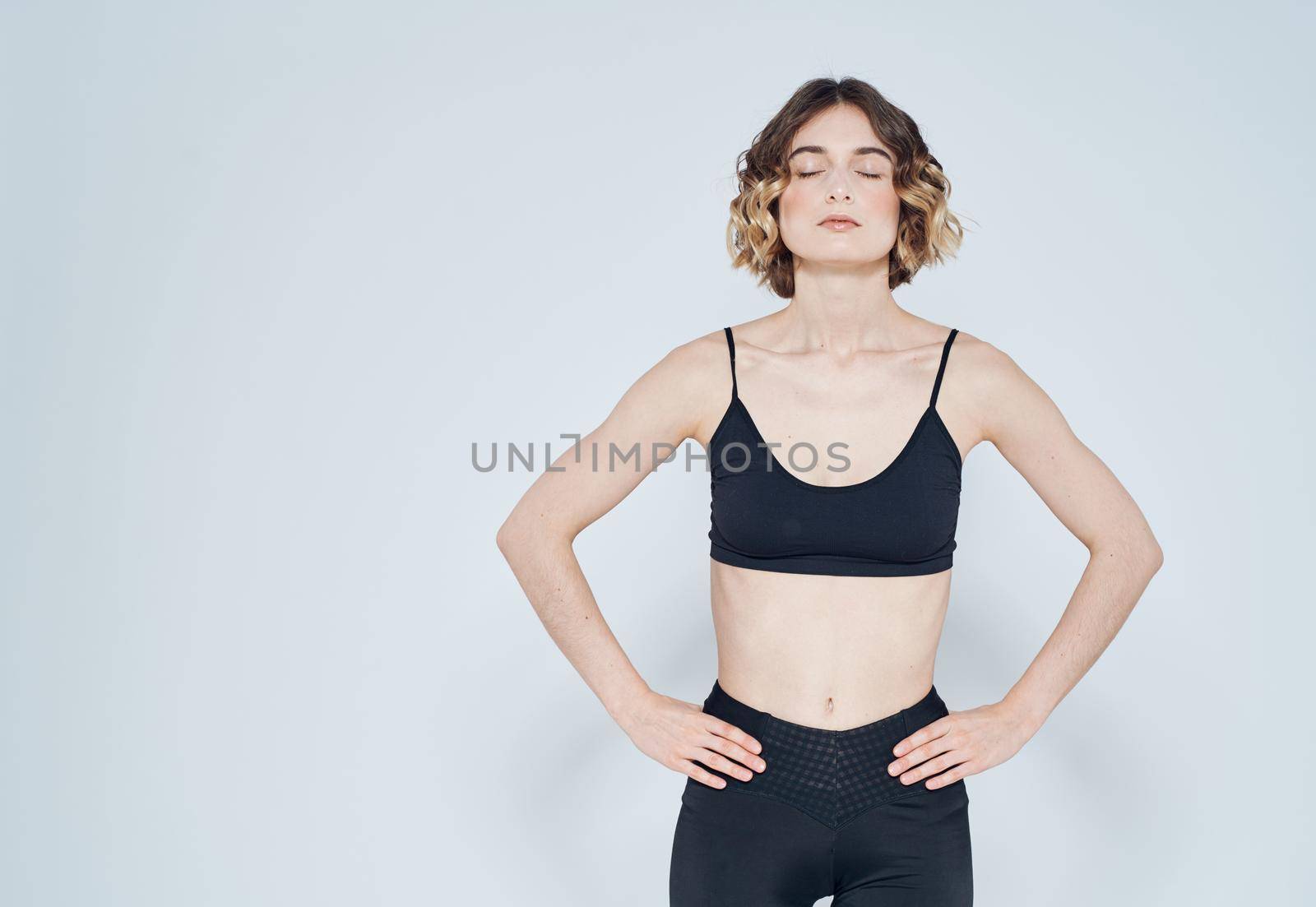 Woman in sportswear keeps her hands on the belt Fitness Model by SHOTPRIME
