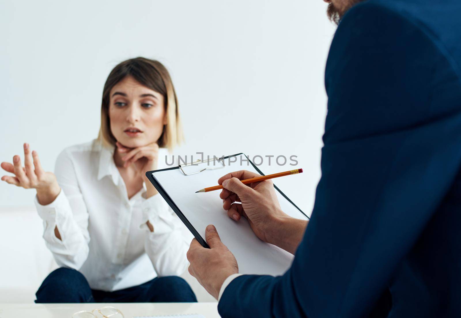 A man in a classic suit with documents in his hands and an emotional woman on the couch. High quality photo