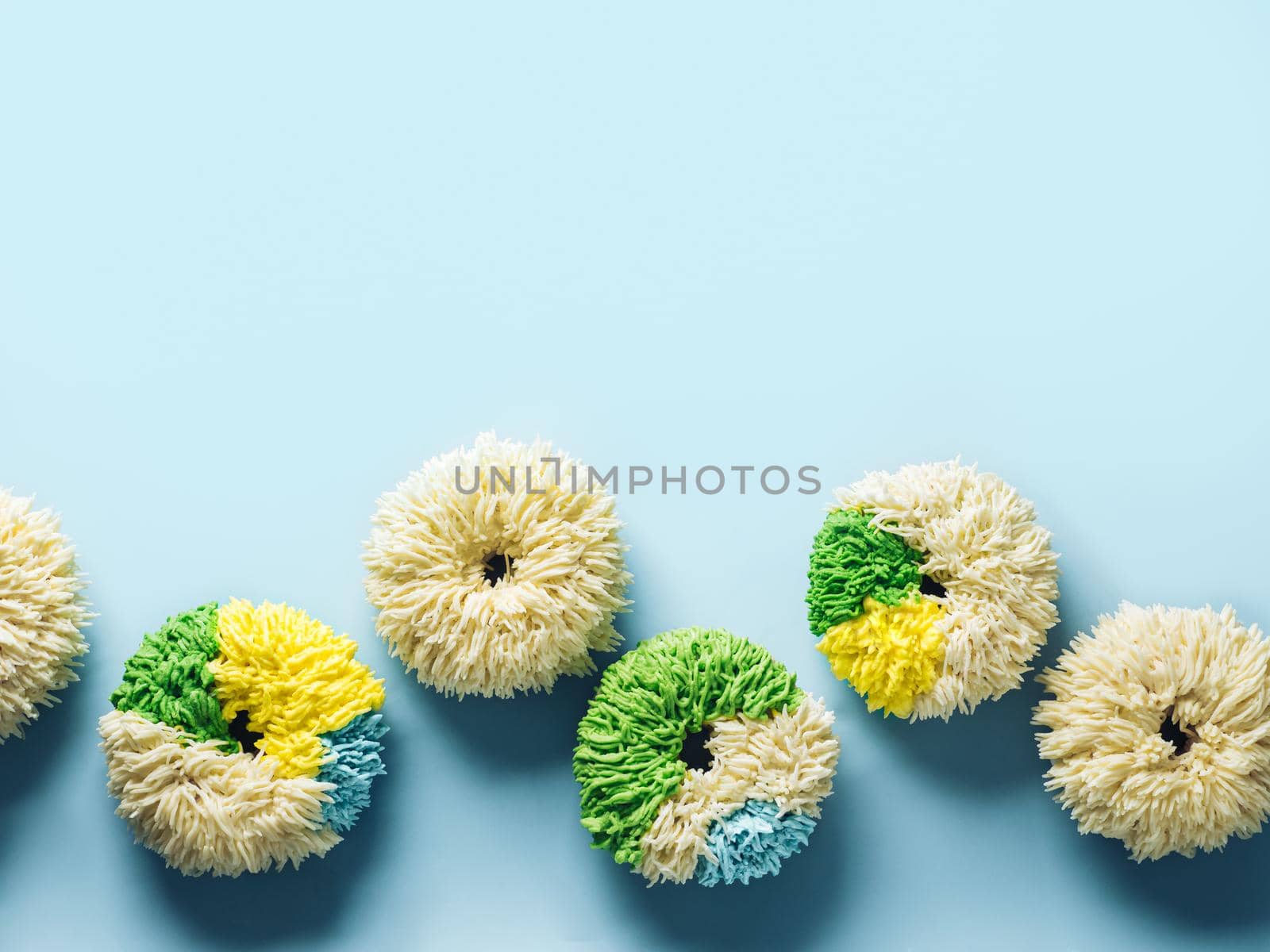 Shag donuts on blue background. Unusual trendy colorful donuts with vanilla buttercream. Copy space. Top view or flat lay.