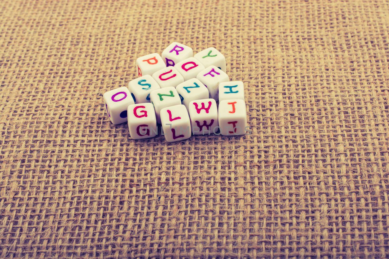 Dice-sized alphabet cubes on textured surface on display