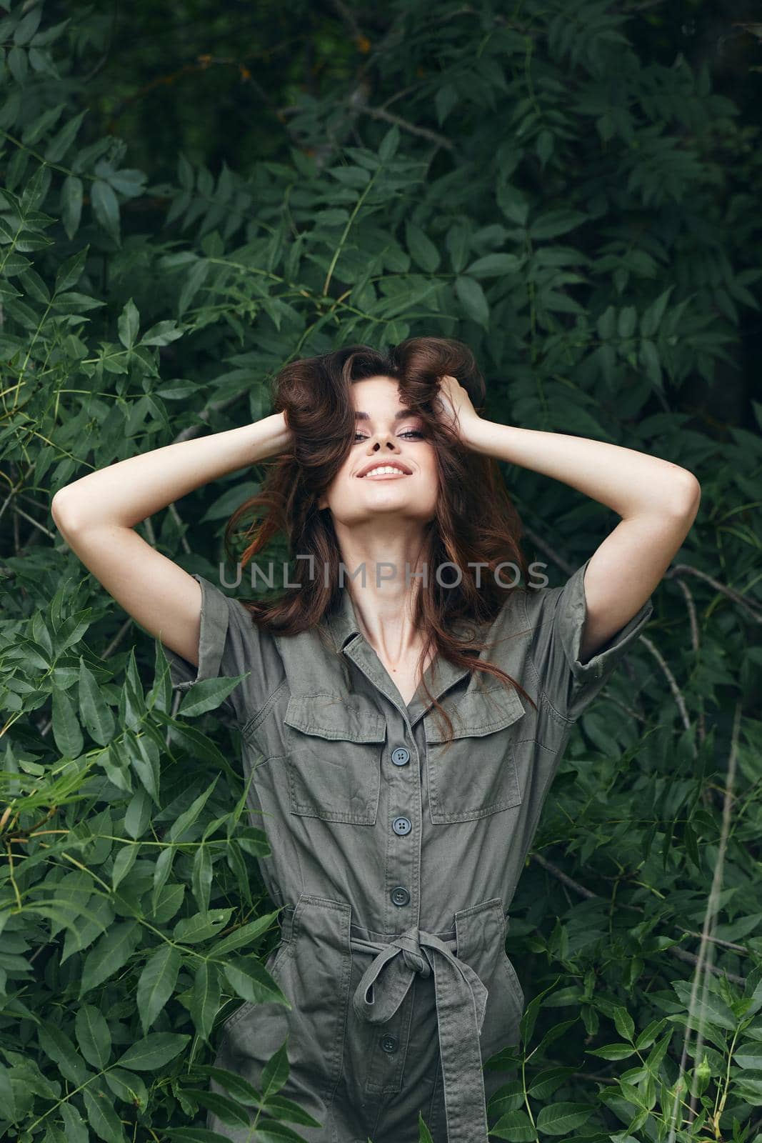 Portrait of a woman pleasure to touch the hair on the head with your hands and a green jumpsui fresh air by SHOTPRIME