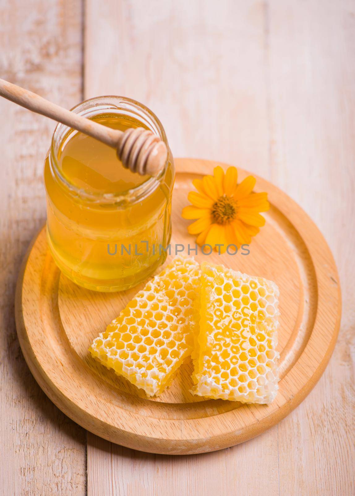 Honey dipper on the bee honeycomb background. Honey tidbit in glass jar and honeycombs.