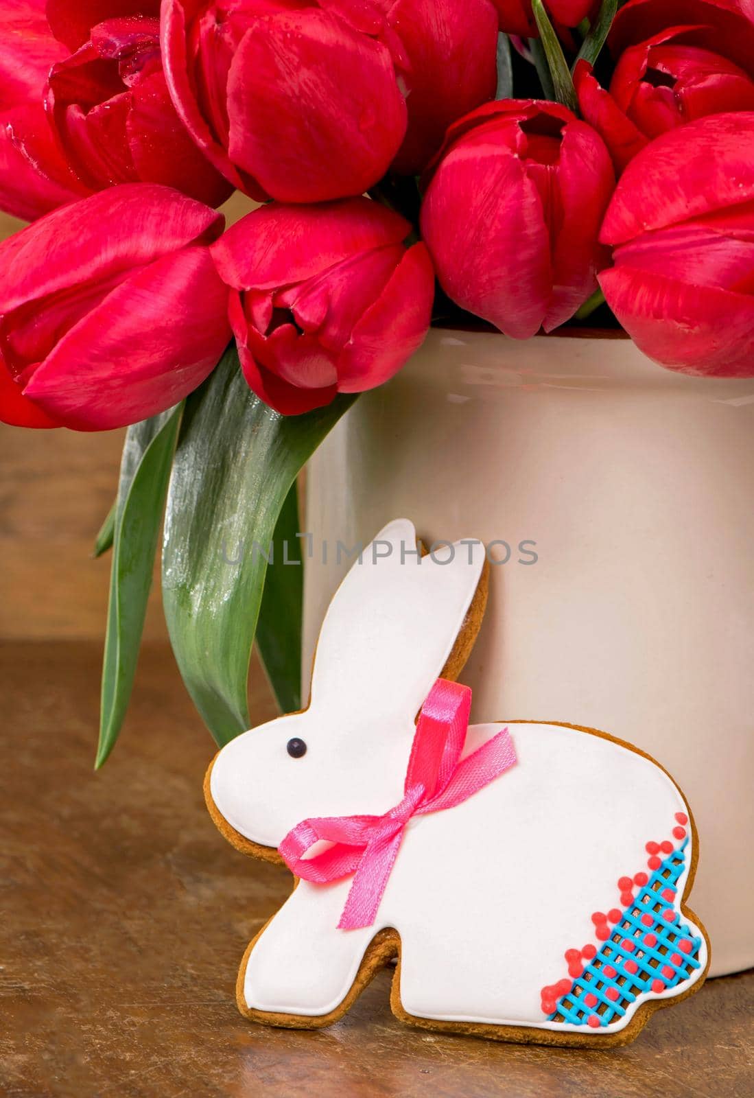 Pink tulips and easter bunny cookie on wooden background. Spring or easter concept