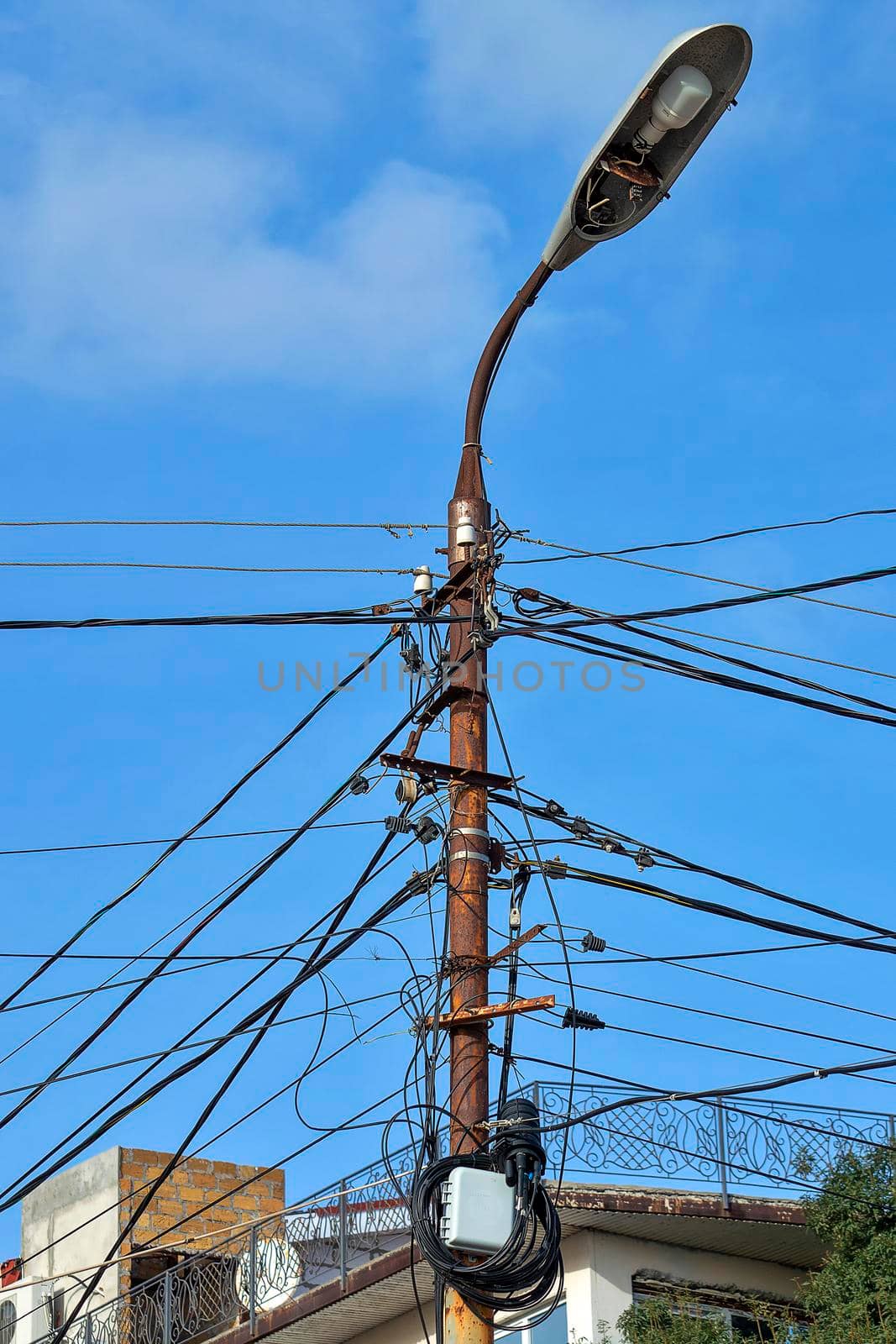 A lamppost with lots of wires. A sunny autumn day is a side view. by Essffes