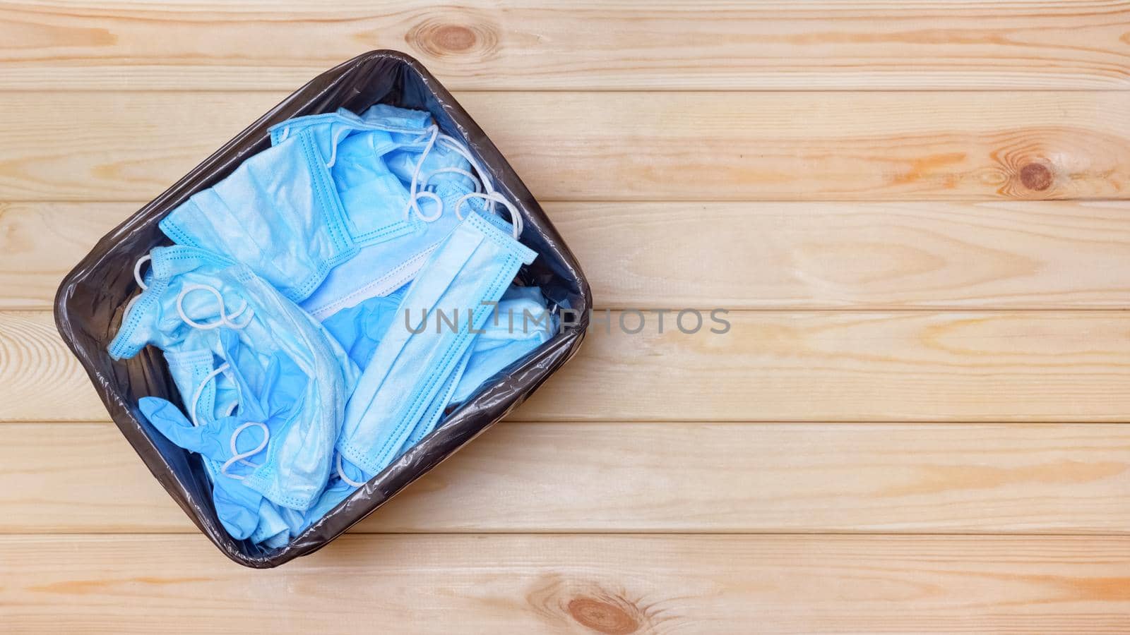 High view of trash can with masks. End coronavirus trash banner garbage bucket with mask infected waste after pandemic is over. Used masks in waste banner bin on floor top view. Post covid office bin