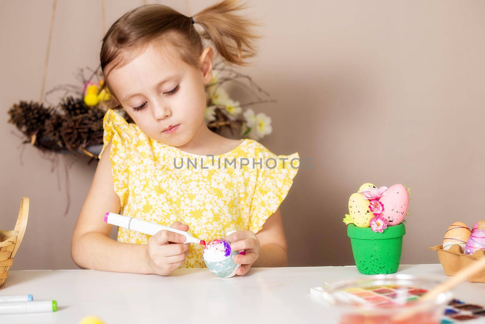 Small Caucasian girl of 5 years old paints eggs with special markers for Easter. by galinasharapova
