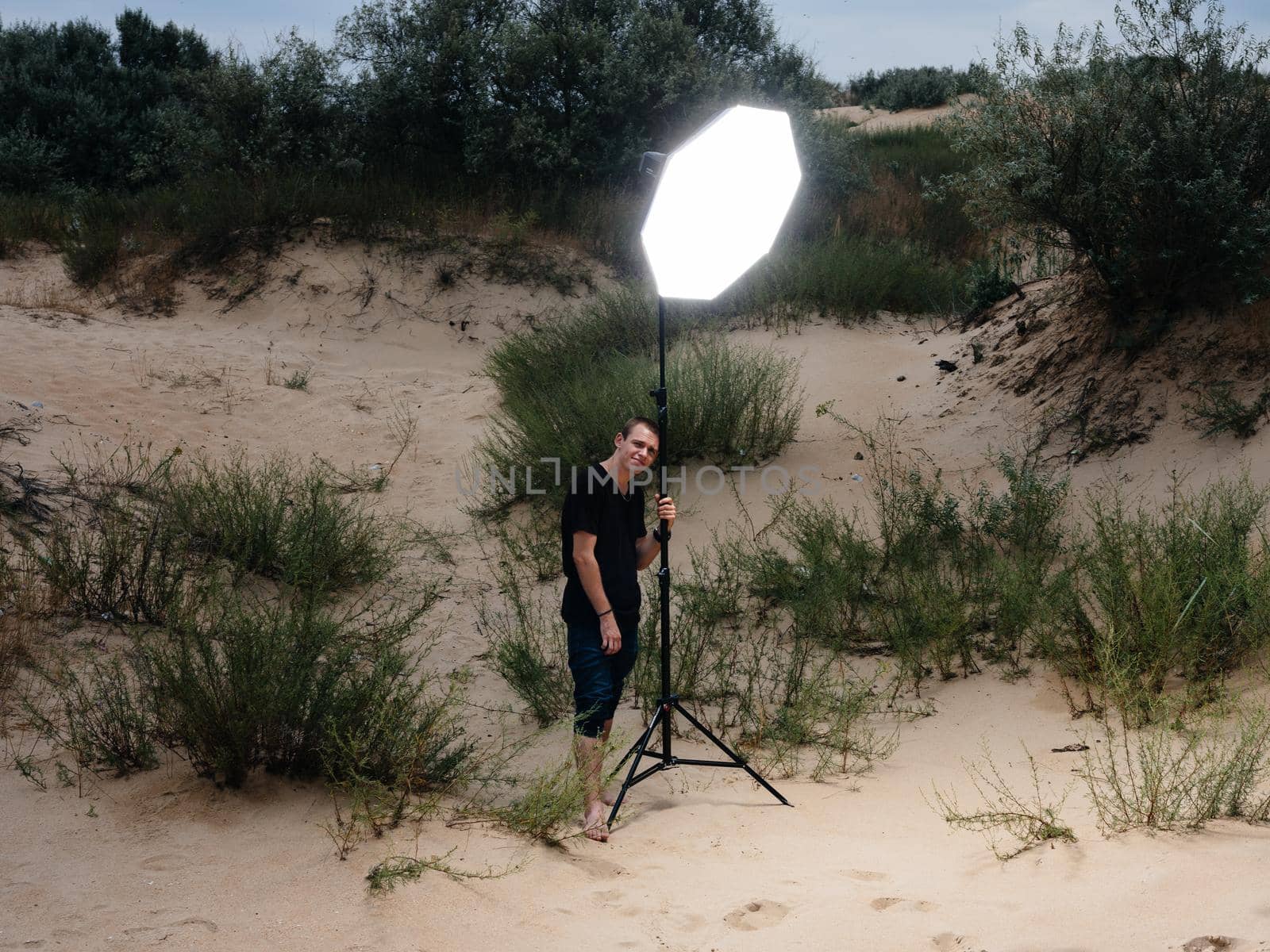 A man with a bright spotlight stands on the sand on an island on the beaches by SHOTPRIME