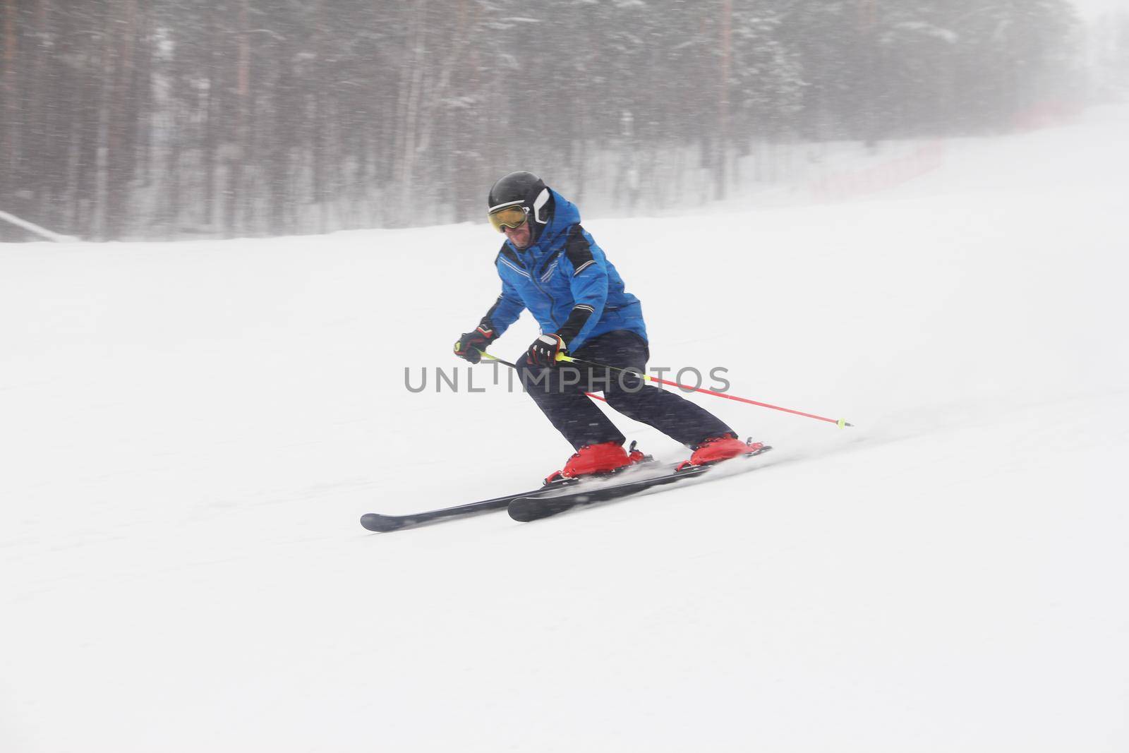 Male skier skiing downhill in mountains snowy day