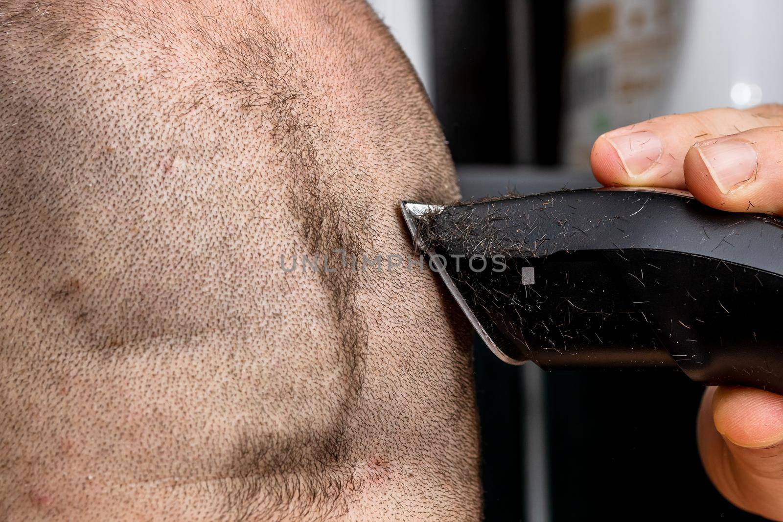 Man shaving or trimming his hair using a hair clipper by vladispas