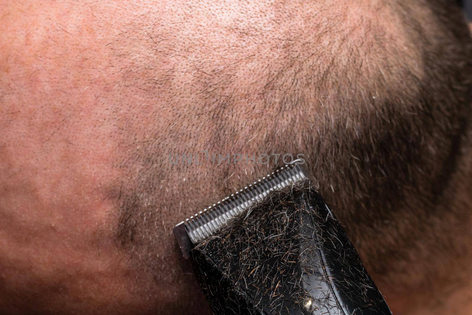 Man shaving or trimming his hair using a hair clipper by vladispas