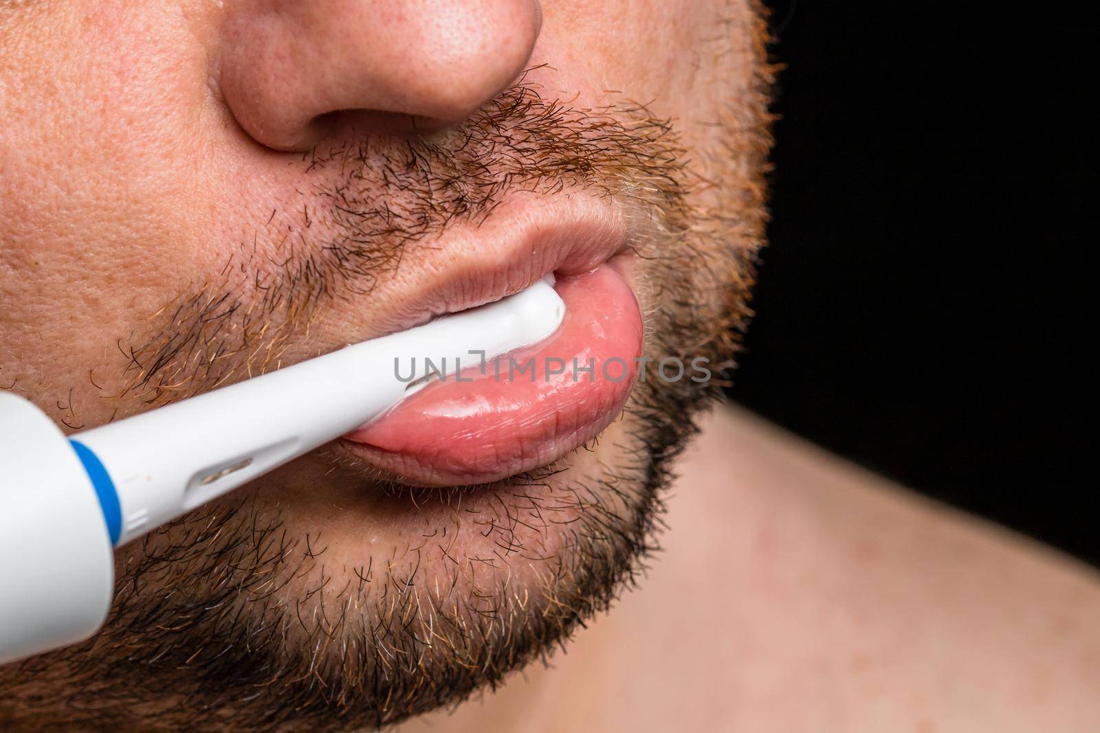 Close up of man brushing his teeth with electric toothbrush by vladispas