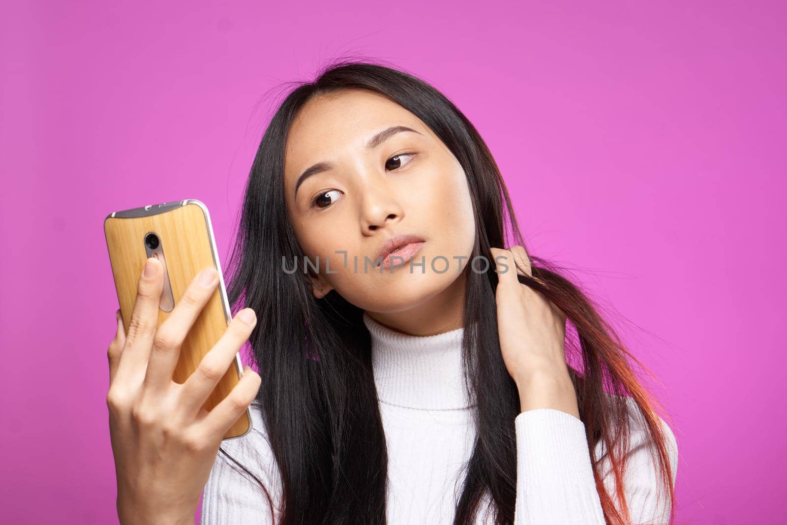 cheerful pretty brunette with a phone in her hands communication internet technology pink background. High quality photo