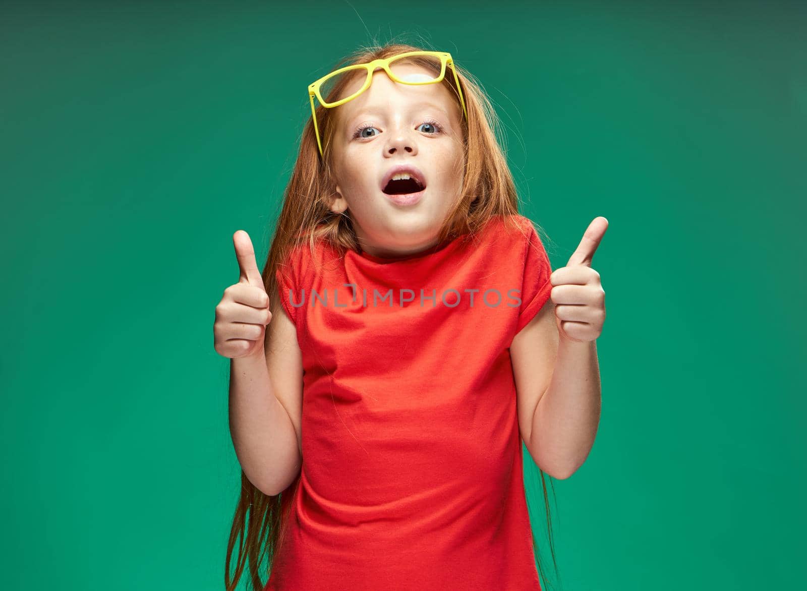 cheerful red-haired girl holding glasses in her hands learning school green background. High quality photo