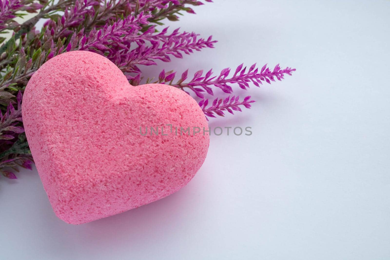 Purple heart bath salt and a branch of artificial lavender on a white background. Space for text.