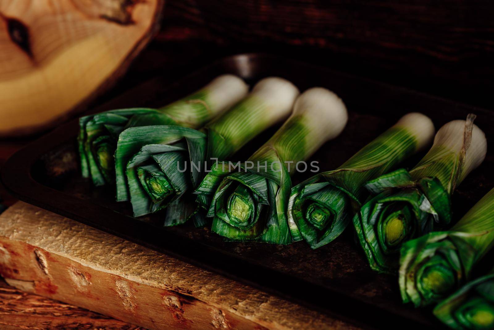 Fresh green leek stalks on rustic tray