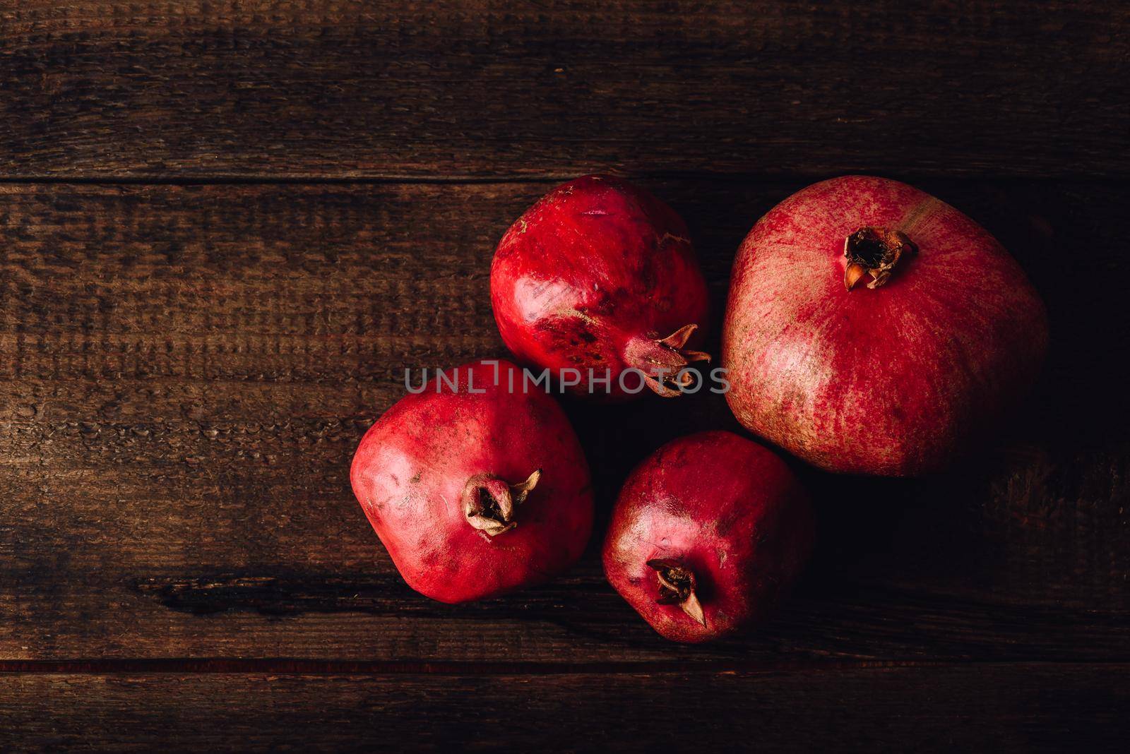 Four ripe pomegranate on rustic wooden table