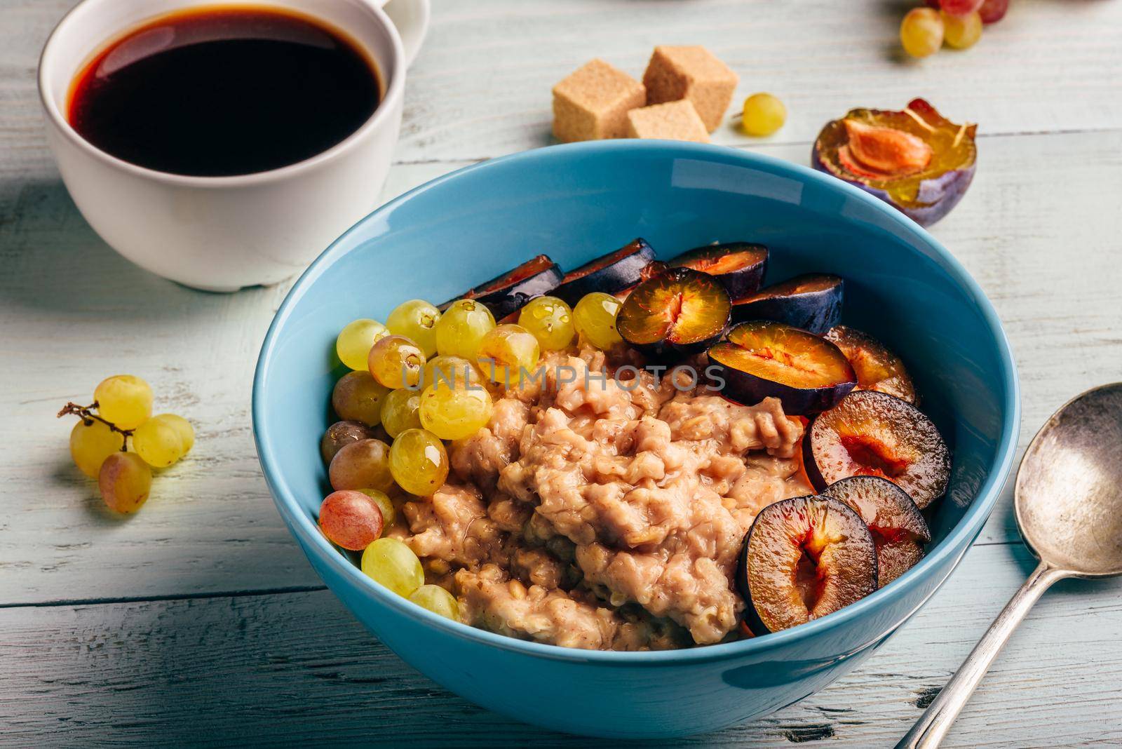 Healthy breakfast concept. Porridge with fresh plum, green grapes and cup of coffee.