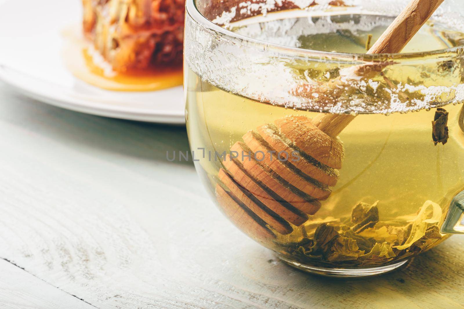 Honey dipper in cup of green tea by Seva_blsv