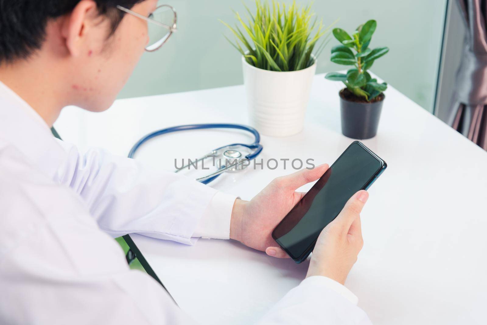 Doctor woman smiling using working with smart mobile phone by Sorapop