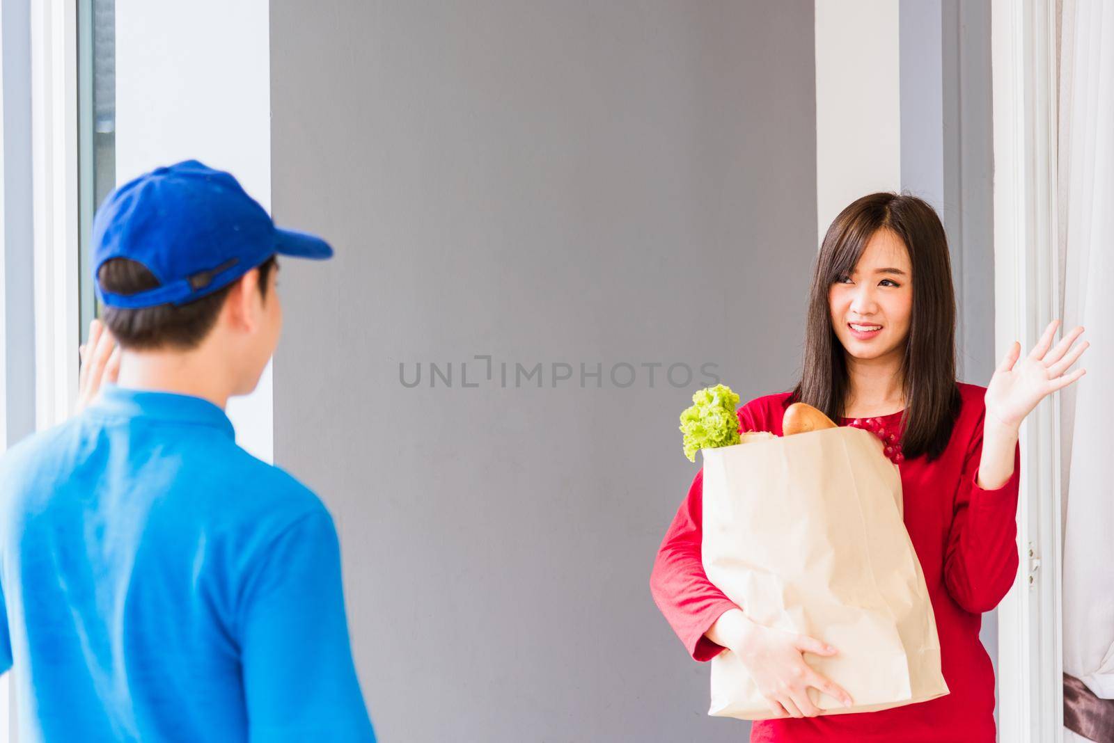 Delivery man making grocery service giving fresh vegetables in paper bag to woman customer by Sorapop
