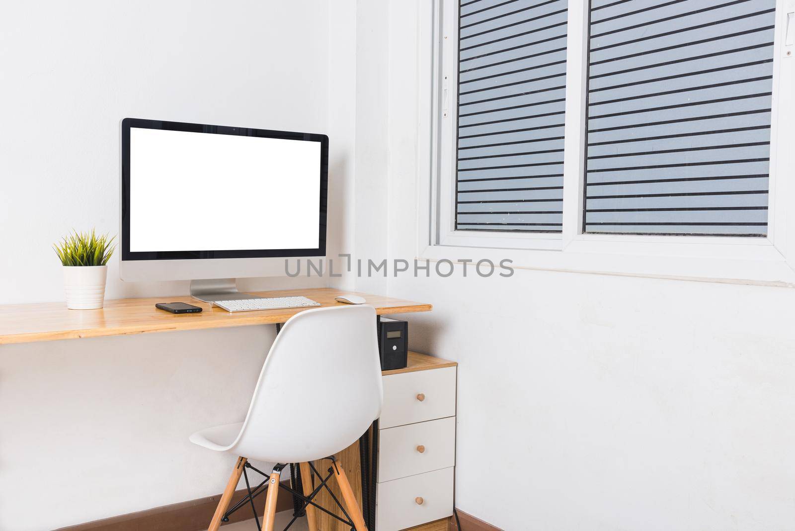 Computer monitor with white blank screen on the business desk with wireless mouse, keyboard at home office over white wall background, Photo of equipment contemporary workspace