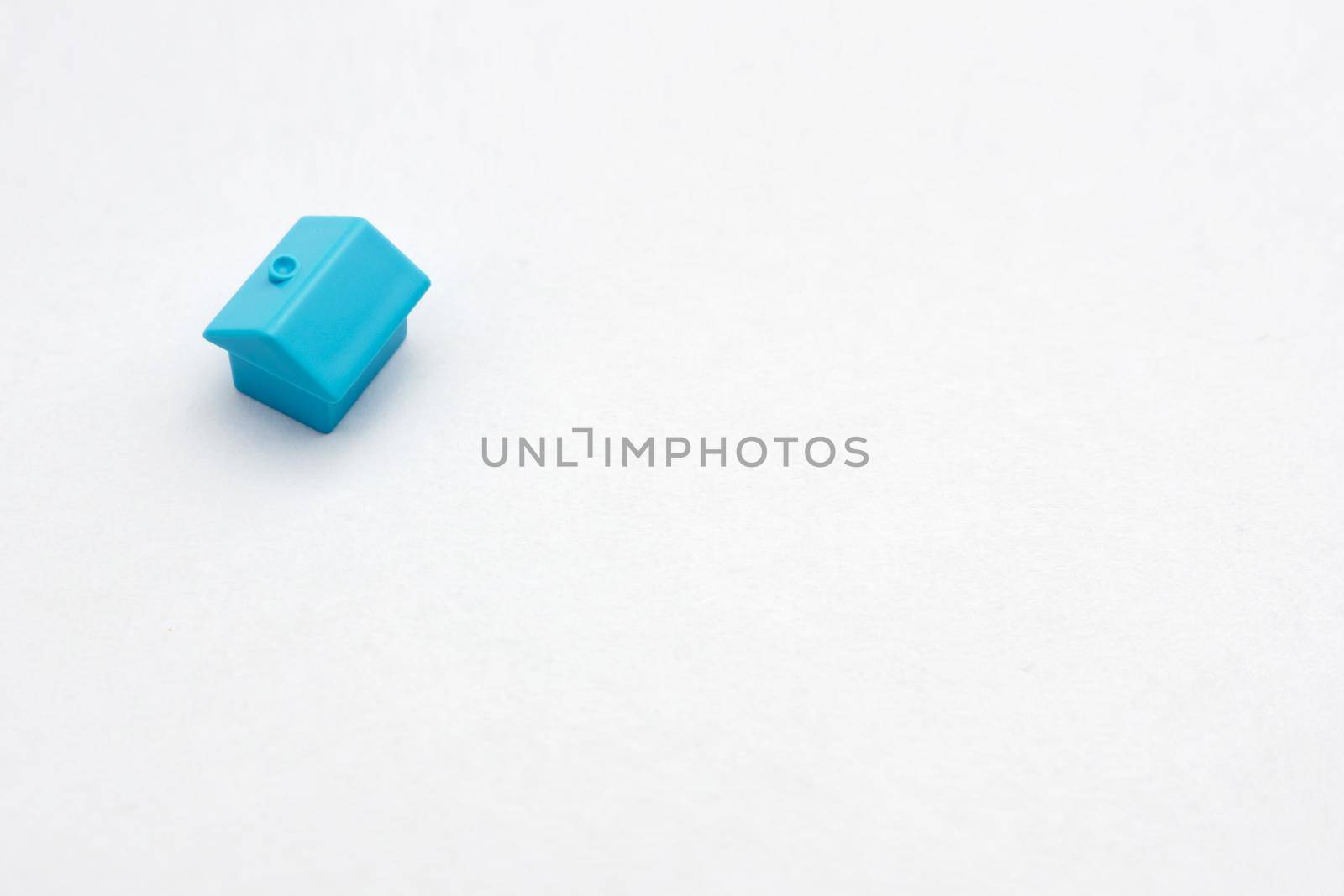 One single blue miniature model house property market. Miniature home on white paper document background business property contract. Real estate buy sell house icon property building home improvement