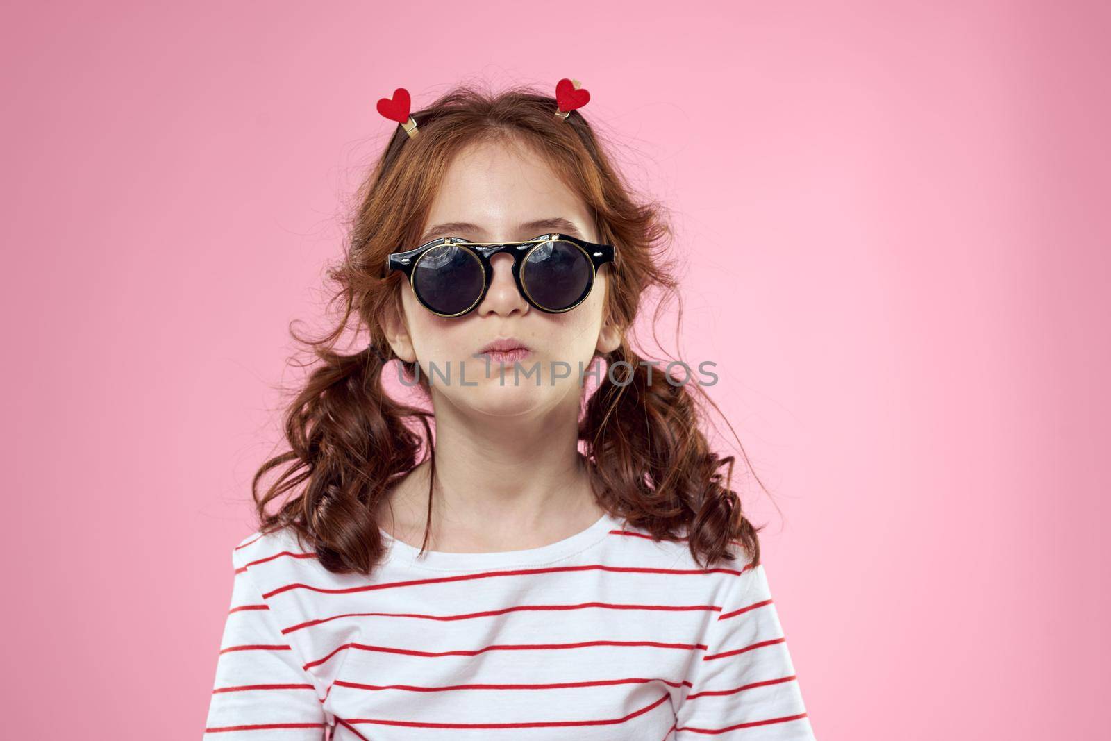 Fashionable girl with clothespins in the form of hearts on her head and glasses on her face. High quality photo