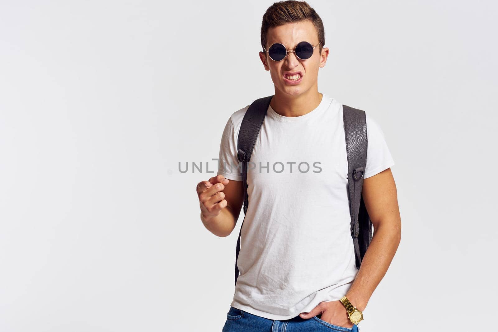 man in sunglasses with a backpack on his back and in a white t-shirt on a light background cropped view of emotion. High quality photo