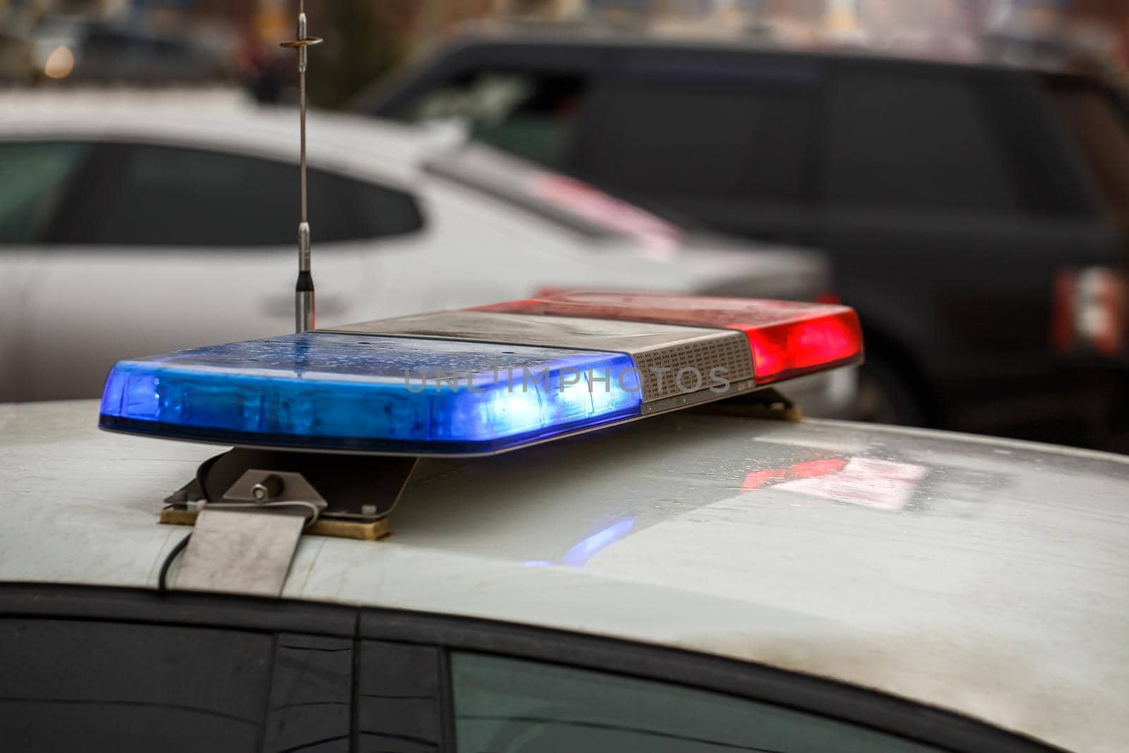 police car lights in city street at winter day with cars traffic in blurry background.