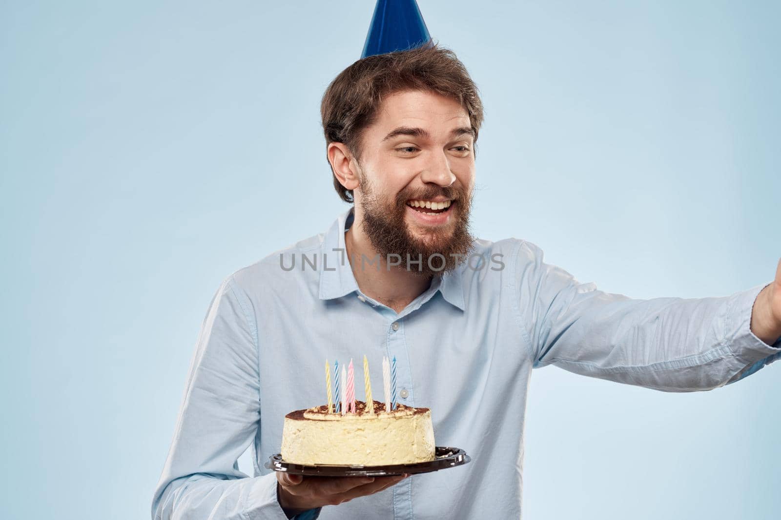 cake in a plate and birthday man with a cap on his head blue backgroun. High quality photo