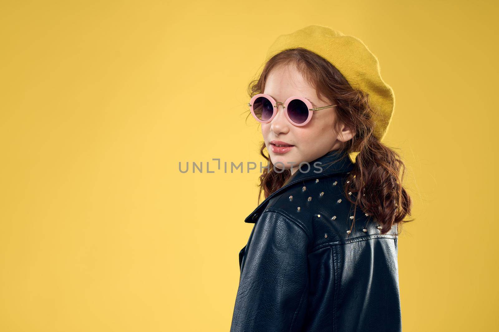 Girl in a yellow hat dark glasses fashionable clothes studio lifestyle childhood. High quality photo