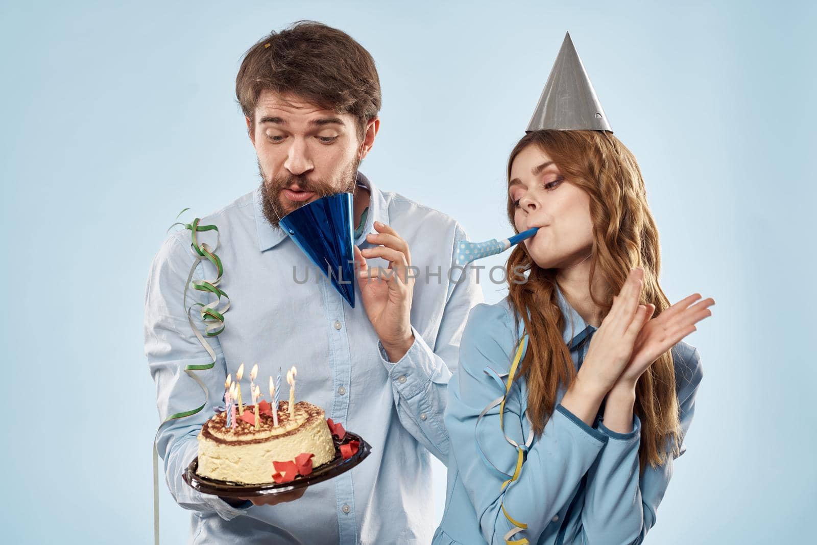 Birthday man woman in party hats on a blue background and cake with candles. High quality photo