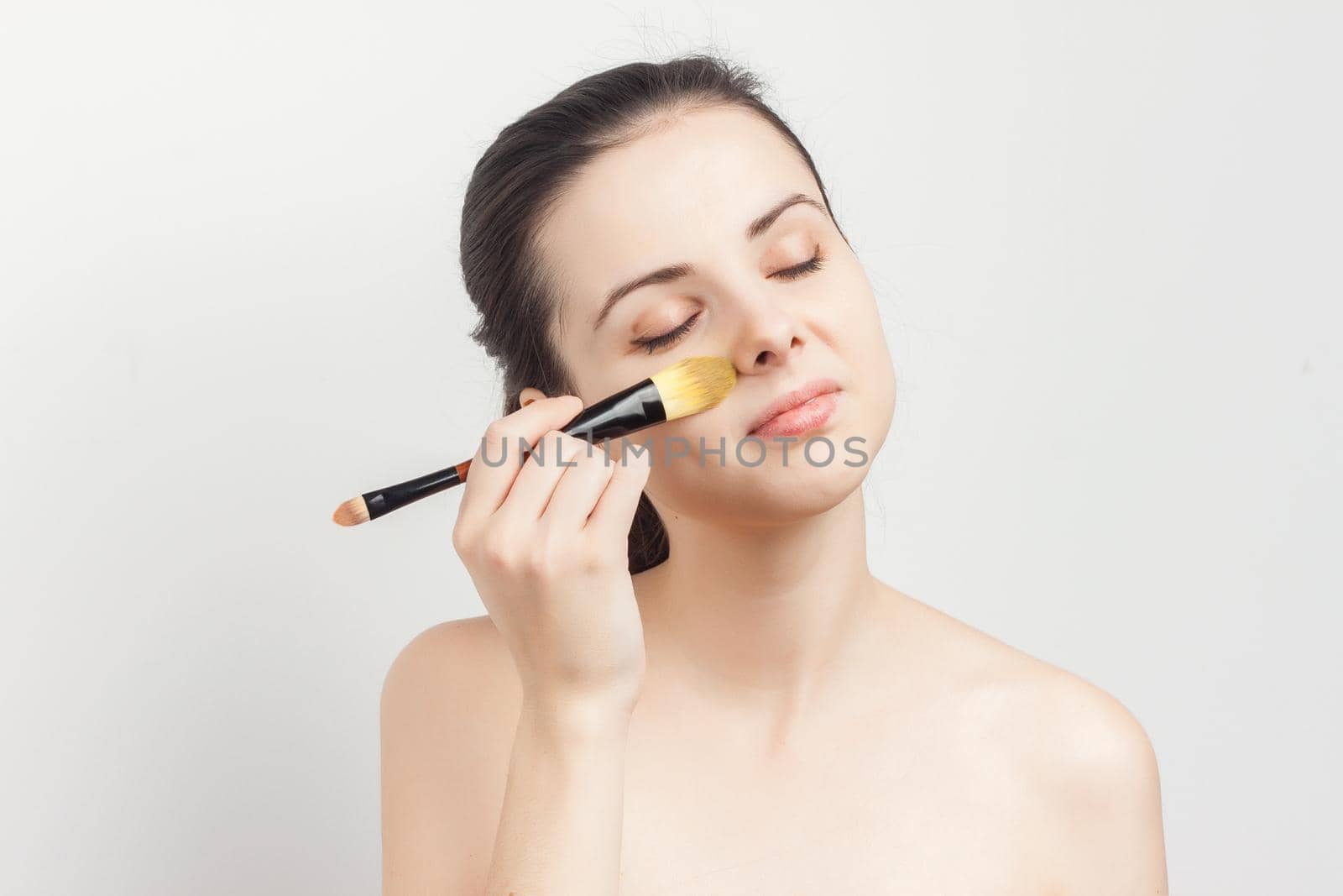 brunette brushing cream on face skin care cropped view. High quality photo
