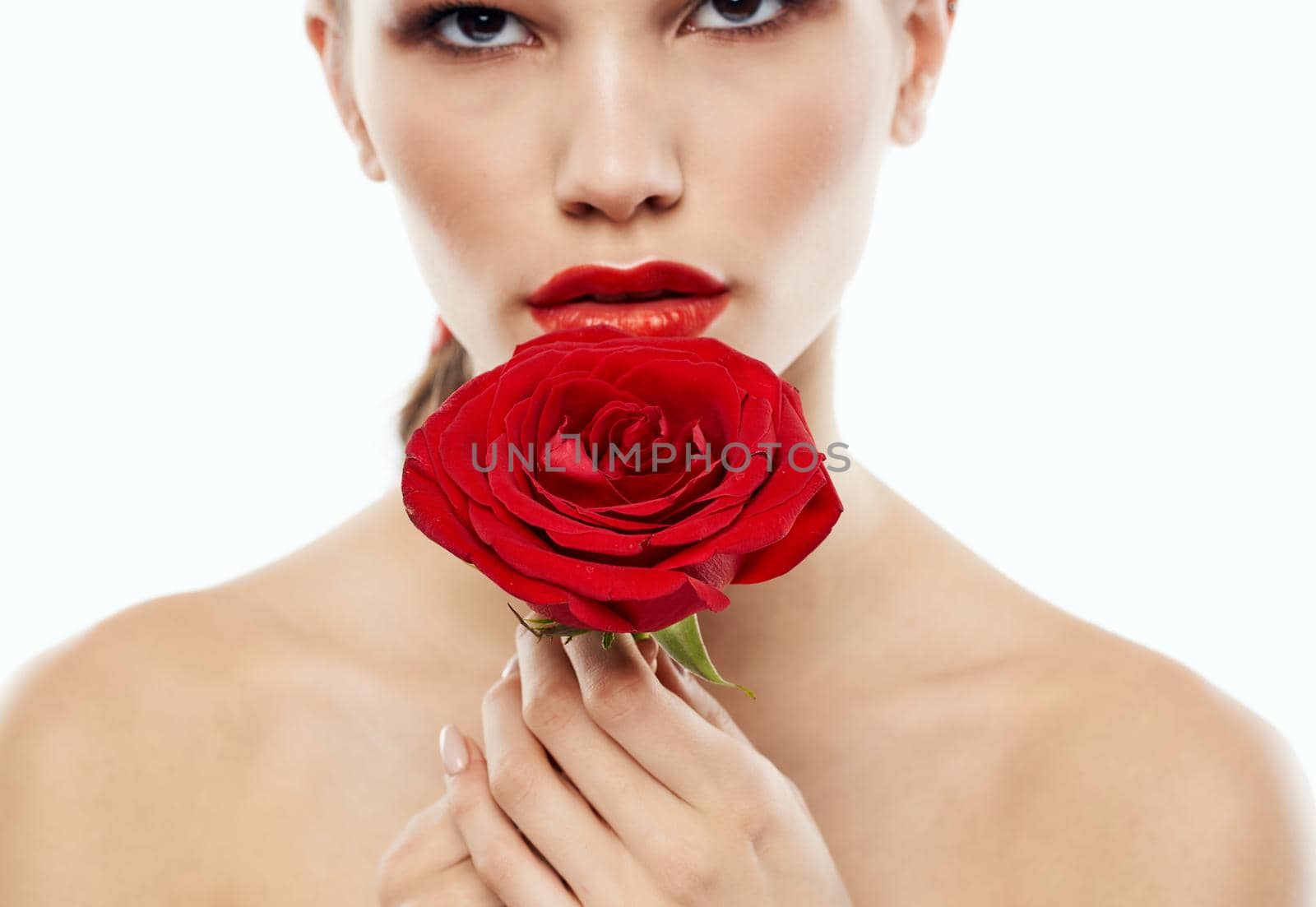 Portrait of romantic people with bare shoulders and a red flower in front of their eyes. High quality photo