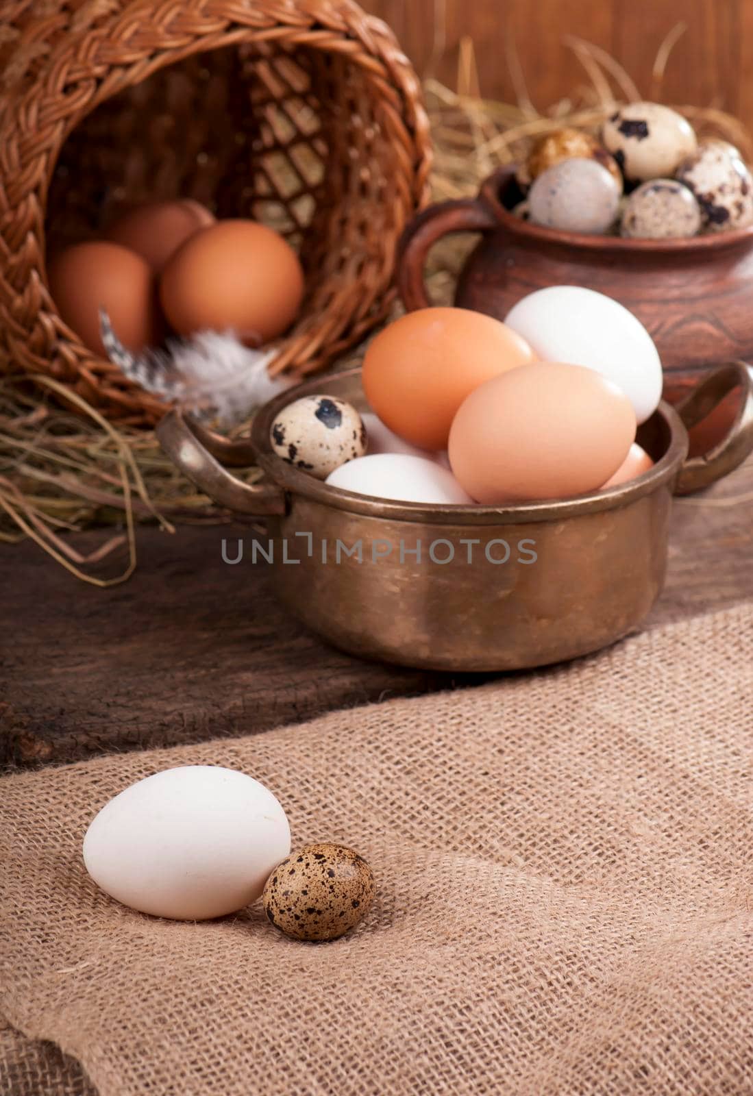 Chicken fnd quail eggsin basket on wooden background by aprilphoto