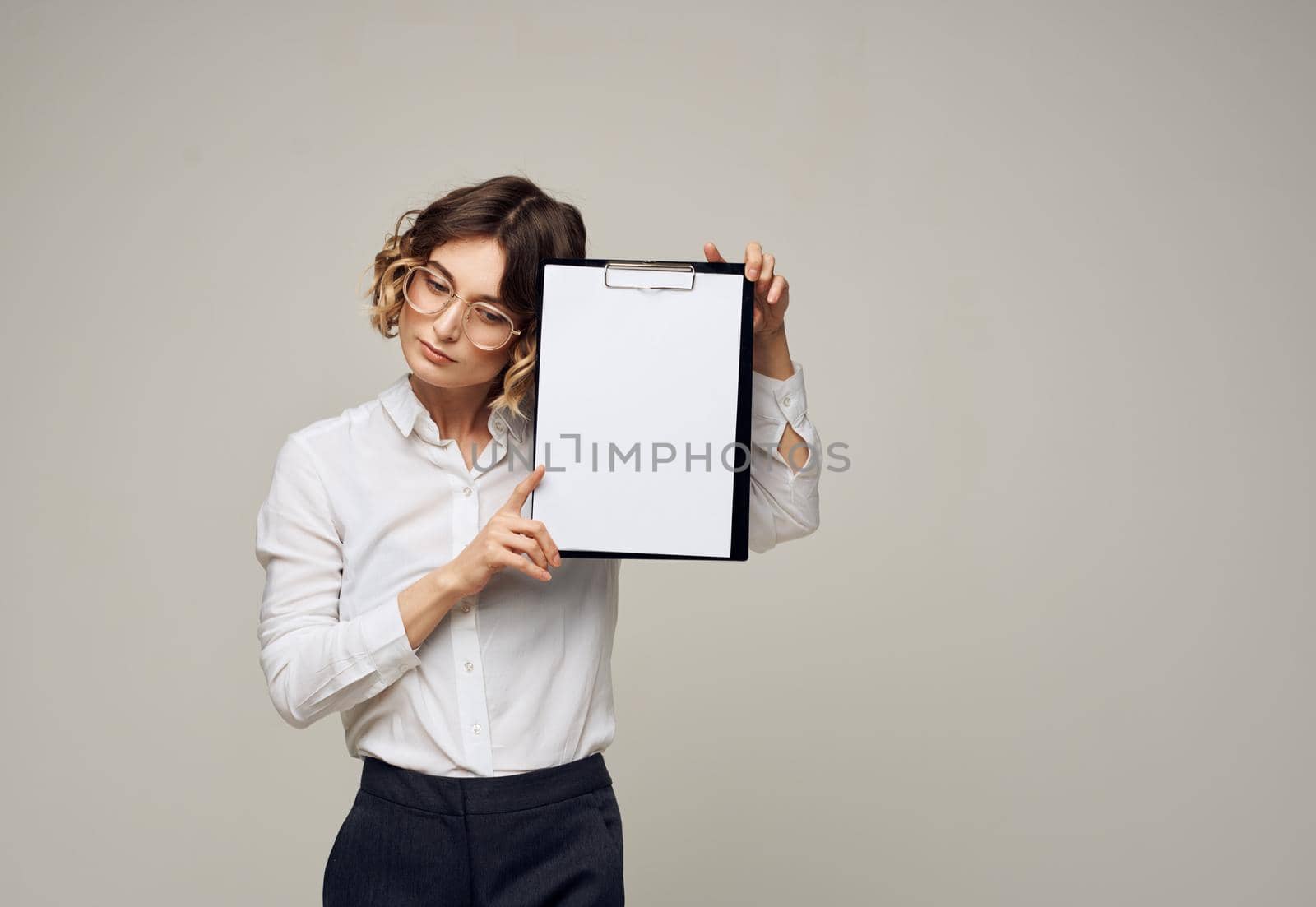 Woman with a white sheet of paper in a folder on a gray background Copy Space. High quality photo