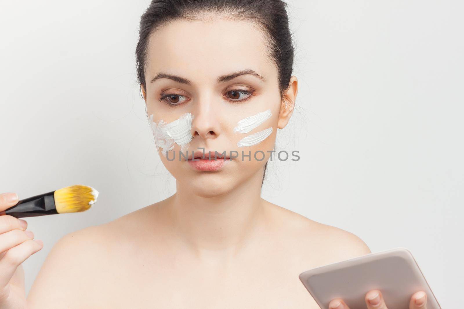 pretty brunette with a brush in her hands applying makeup skincare procedures. High quality photo