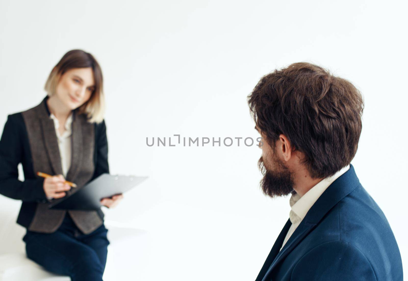Business woman in a classic suit and a man in a jacket on a light background opposite each other. High quality photo