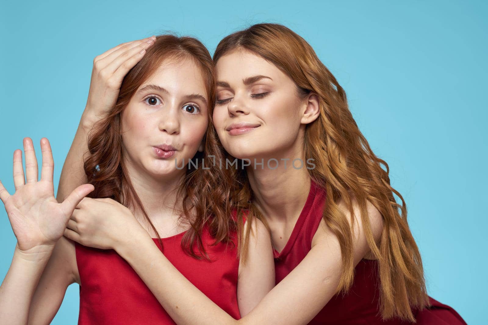 Cheerful mom and daughter hugs joy lifestyle communication friendship blue background. High quality photo