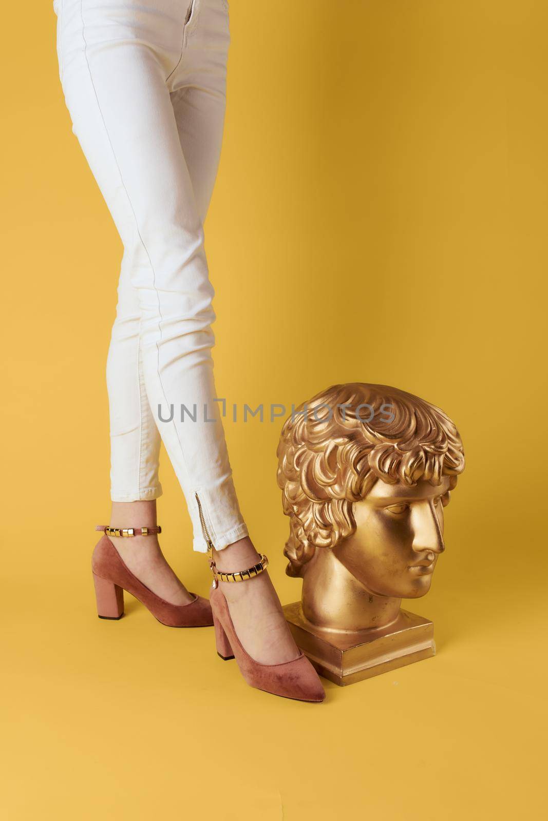 Female feet head sculptures golden color luxury fashion yellow background. High quality photo