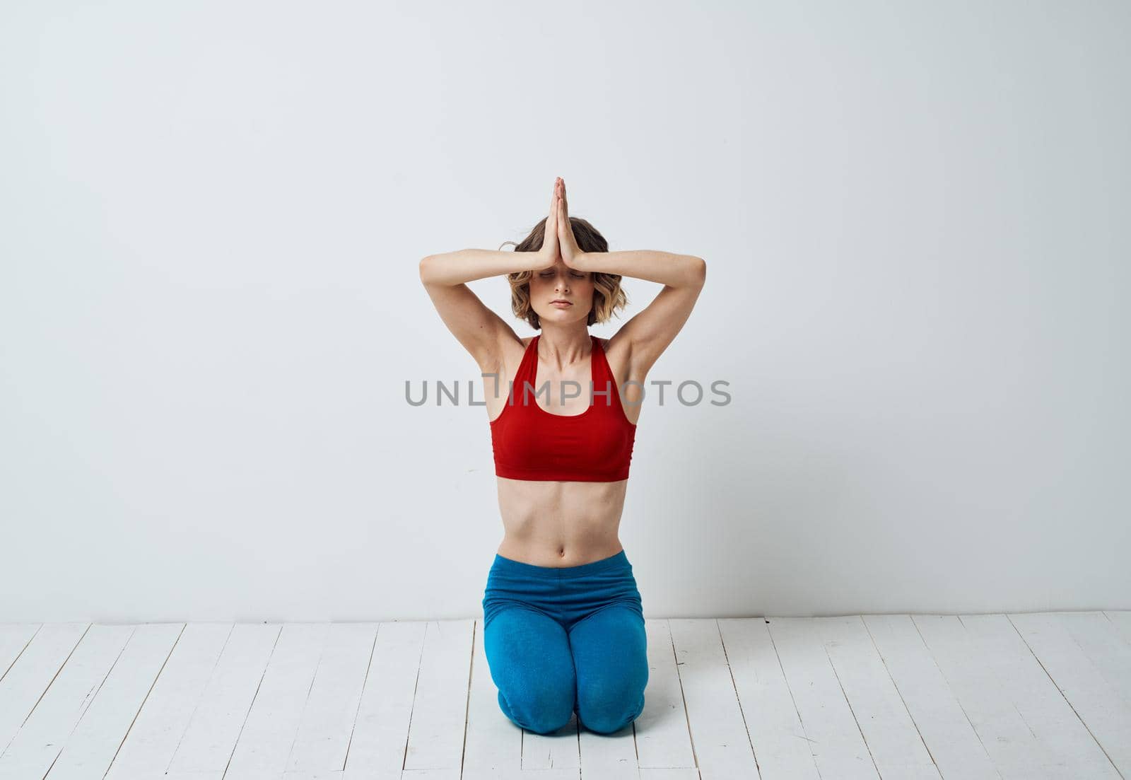 A slender woman is engaged in yoga for beginners on a light background in full growth by SHOTPRIME